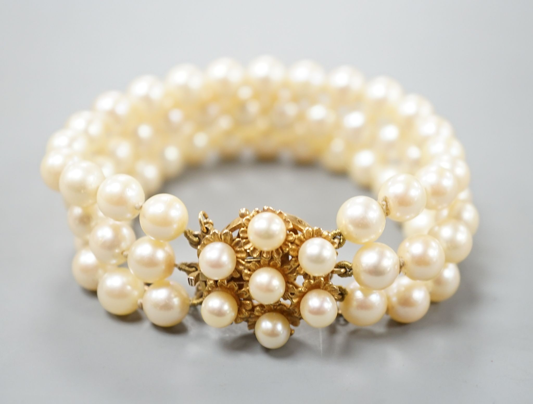 A triple strand cultured pearl bracelet, with yellow metal and cultured pearl cluster set clasp, approx. 16cm.